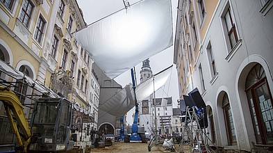 In einem Filmset in historischer Kulisse in Görlitz sieht man Filmschaffende und einen Leuchtschirm sowie weitere Filmtechnik.