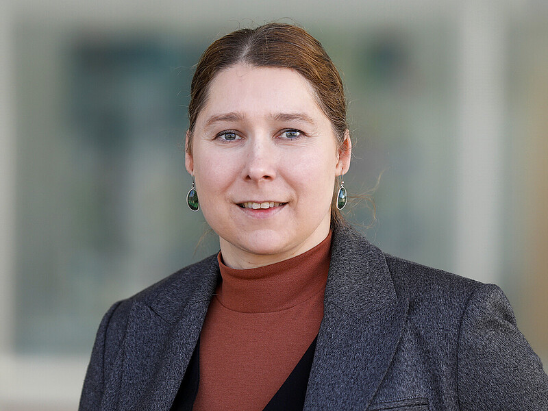 Prof. Dr. rer. nat. Elisa Wirthgen stands in front of a building and smiles into the camera.