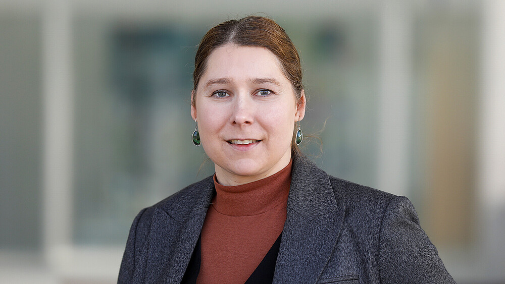 Prof. Dr. rer. nat. Elisa Wirthgen stands in front of a building and smiles into the camera.