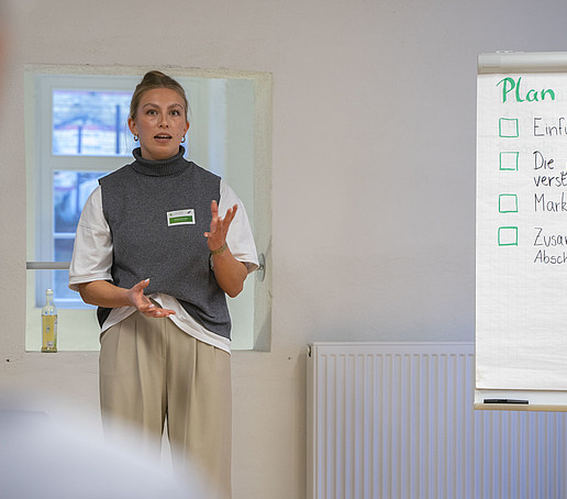A participant stands next to a flipchart and explains something to the audience.
