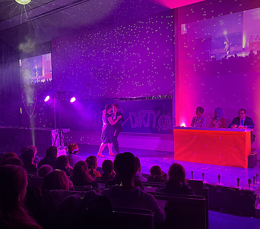 The jury watches a dancing couple on stage.