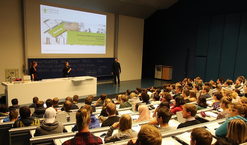 The advisors for foreign students introduce themselves in a lecture hall full of students.