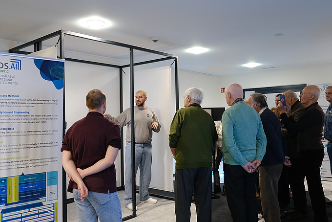 Senior citizens stand in the corridor and listen to a speaker.