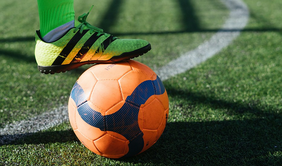 Fuß von einem Fußballer, der auf einem Ball steht.