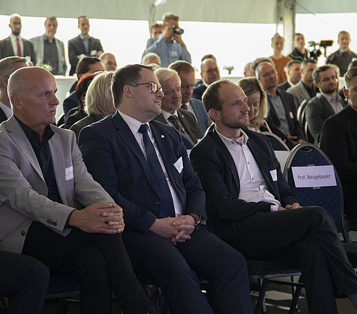 In the audience, many guests sit in several rows of seats.