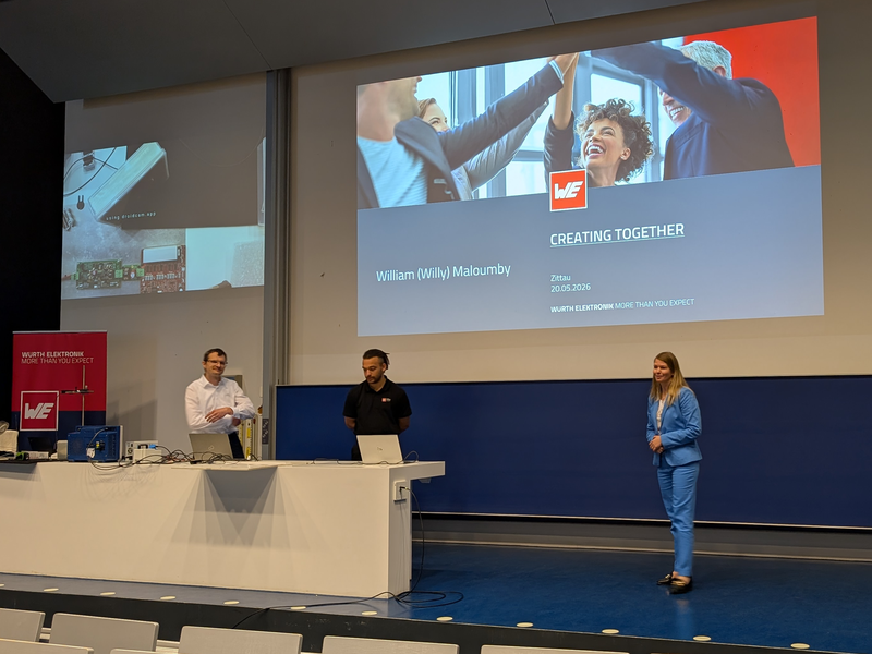 Three people in a lecture room in front of a projector image for a lecture