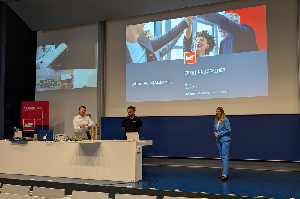 Three people in a lecture room in front of a projector image for a lecture