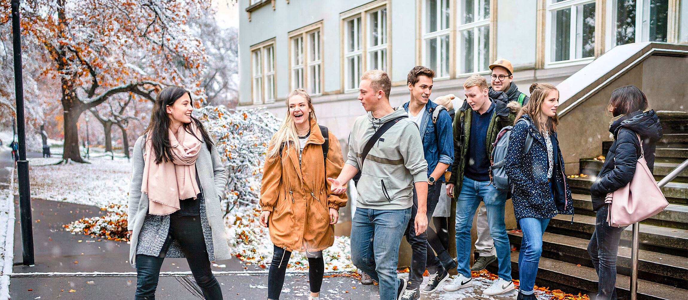 Students walk out of house 2 and talk to each other in a wintry atmosphere