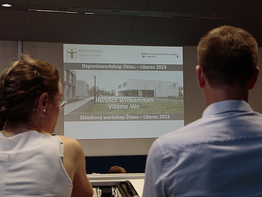 Two workshop participants look at the beamer projection for the recycling and landfill workshop in the lecture hall.