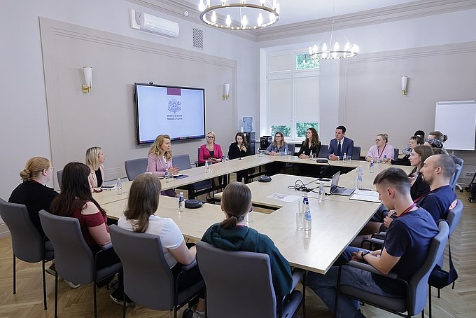 Group of around 17 people sitting at tables in Carré form