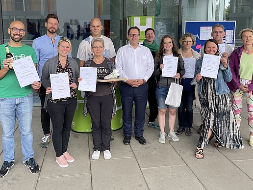 A group of pedometer challenge participants stand in front of House Z 4 and show off their certificates.