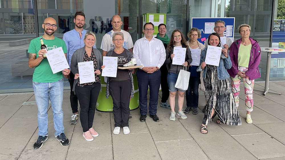 A group of pedometer challenge participants stand in front of House Z 4 and show off their certificates.