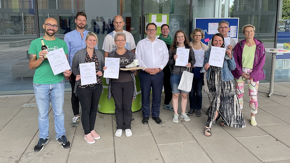 Eine Gruppe Schrittzähler-Challenge-Teilnehmender steht vor Haus Z 4 und zeigt ihre Urkunden.