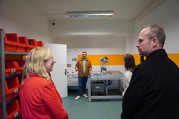 Vice Rector and Prof. Hoff look each other in the face, in the background a SCO-TTi employee stands next to a test facility.
