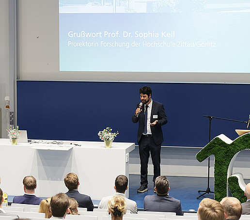 Prof. Scholz hält eine Rede auf dem Podium.