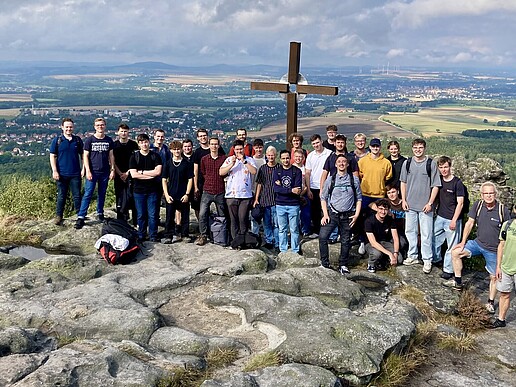 Ein Panoramablick vom Töpferberg zeigt die beeindruckende grüne Landschaft. Neben einer Wandergruppe sind Felsformationen zu sehen.