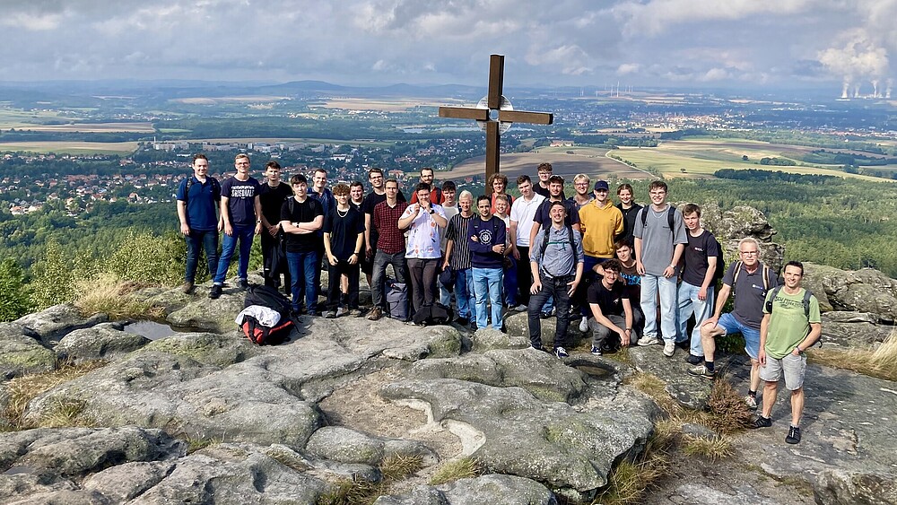 A panoramic view from the Töpferberg shows the impressive green landscape. Rock formations can be seen next to a group of hikers.