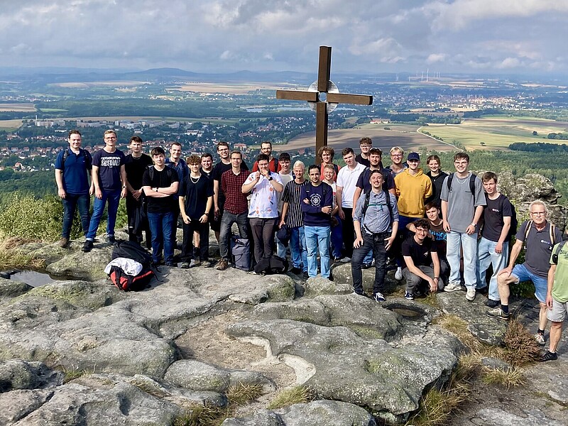 A panoramic view from the Töpferberg shows the impressive green landscape. Rock formations can be seen next to a group of hikers.