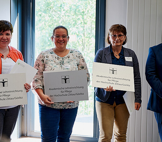 Rector with three cooperation partners in the care sector. They are holding their figurehead and certificate in their hands.