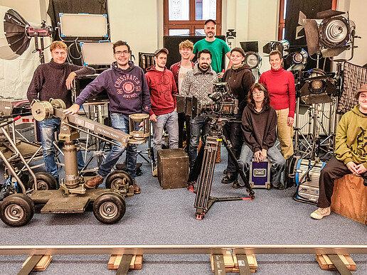 The participants of the course "Assistance Camera, Light & Dolly" are sitting in the seminar room with film equipment around them.