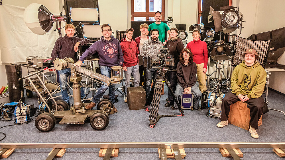 Die Teilnehmenden des Kurses „Assistenz Kamera, Licht & Dolly“ sitzen im Seminarraum, um sie herum Filmausstattung.