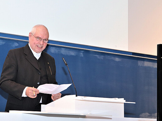 Mann im schwarzen Jacket hält eine Rede