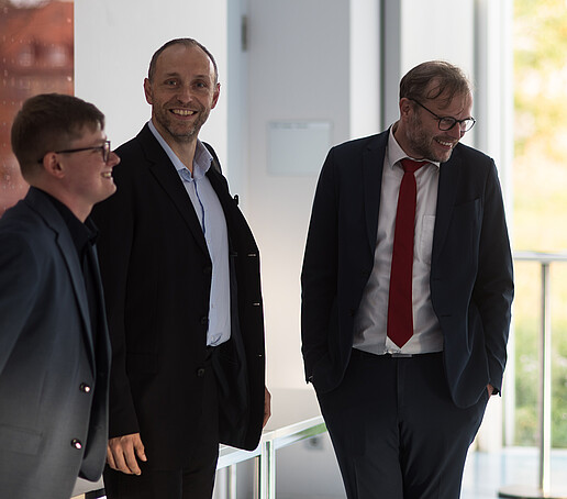 Three men are standing together.
