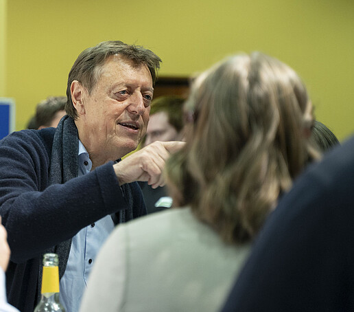 A guest points to something in the room during a conversation.