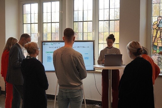 Employees stand in front of a presentation screen.