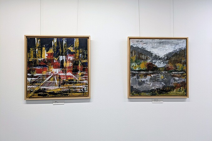 Two paintings hang side by side on a white wall.