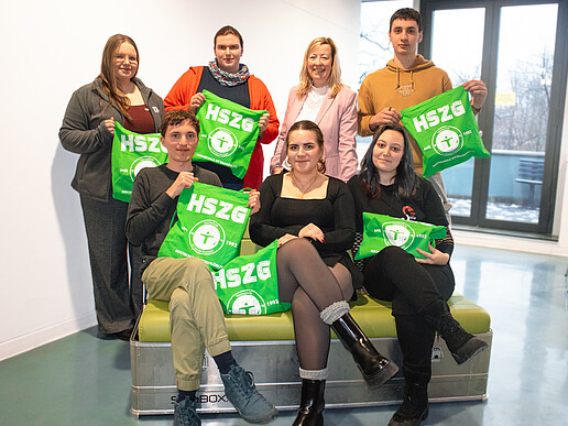 Participants in the CampusCompass project and the Vice-Rector hold up green HSZG bags.