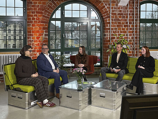 Morning Show participants sit on green sofas in the TV studio.