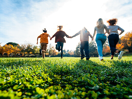 Young people running across a meadow.
