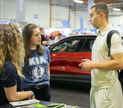 Two employees talking to a visitor at the KIA stand.