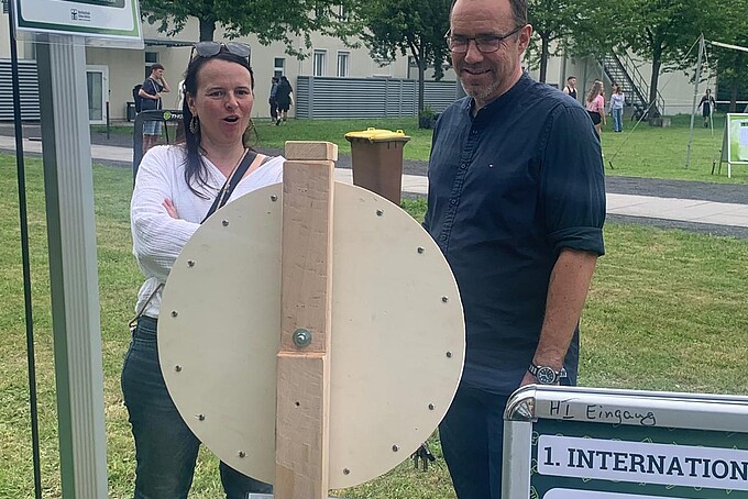 Two employees are standing in front of the wheel of fortune and chatting.
