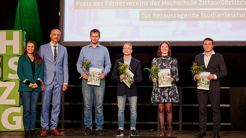 Association members and award winners with their certificates on stage.