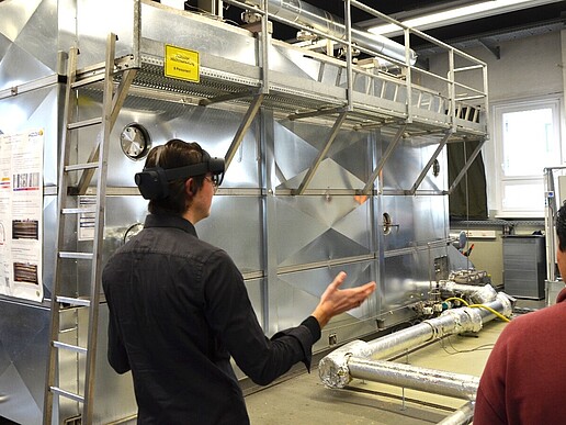 The two Mexican students Juan and Jorge (from left to right) during the live demonstration of their AR application. They are standing in front of a test facility, Juan is wearing VR glasses.