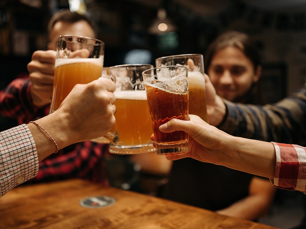 Personen stoßen Biergläser aneinander