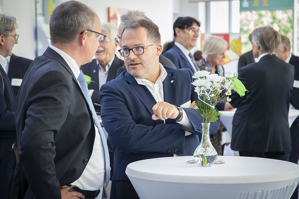 Rector at a high table in the foyer of house four in conversation with a guest
