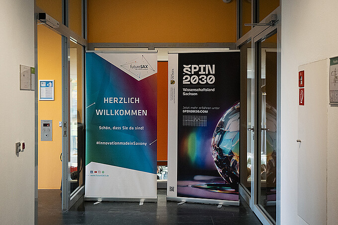 Two roll-ups stand in the corridor of the university that leads to the auditorium.