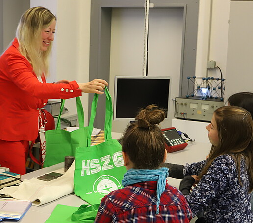 The Vice Rector presents the young schoolgirls with an HSZG bag.