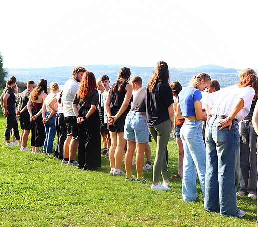 Students stand in a row on a meadow.