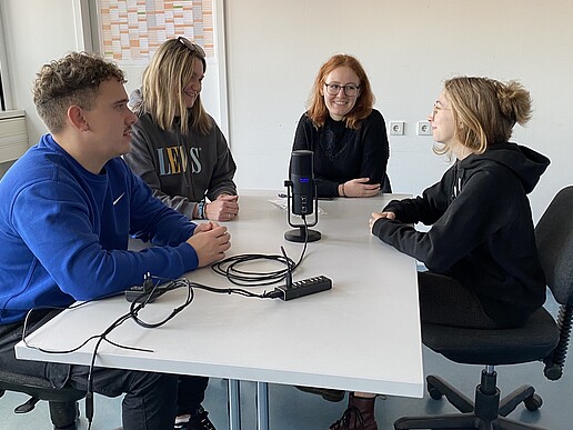 A group of students is sitting at a table chatting.