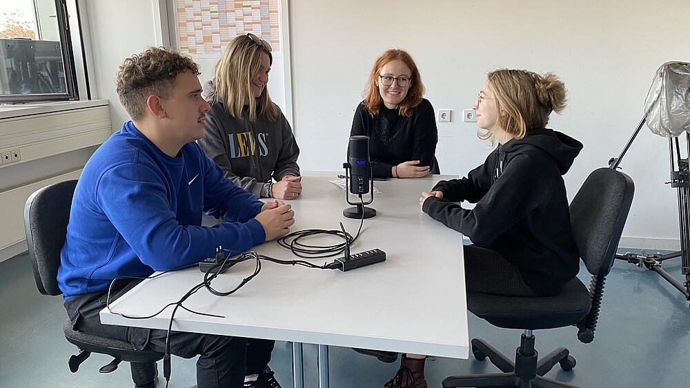 Eine Gruppe Studierender sitzt am Tisch und unterhält sich.