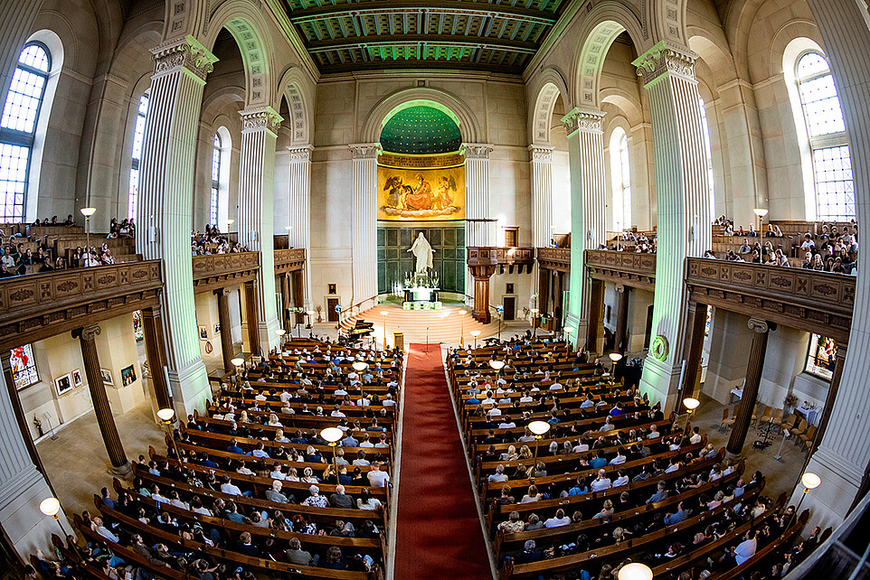 View from the gallery into the packed St. John’s Church in Zittau, with the altar area illuminated in green and HSZG cubes.