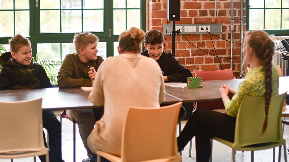 Das Organisationsteam des Wissenschaftskino auf dem Dorf sitzt im Celsiuz an einem Tisch und berät sich.