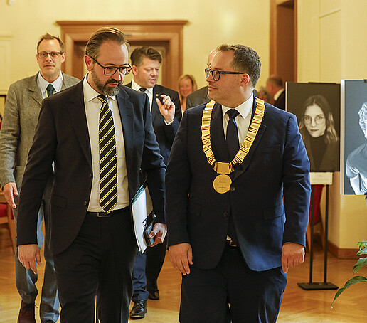 The Minister of Science and the Rector enter the foyer next to the Council Chamber, where a photo exhibition has been set up.