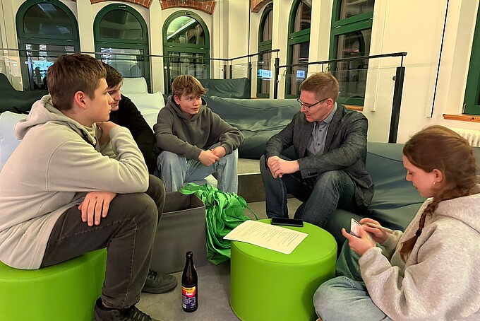 Students sit on green stools and talk to a counselor.