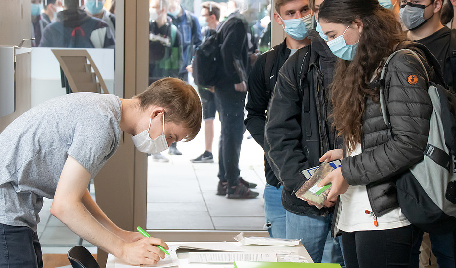 Foto: Christiane Matthieu Studierende stehen vor einem Tisch und schreiben sich für die Come-In-Veranstaltung ein.