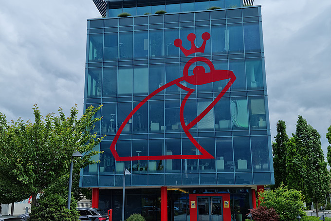 Glasgebäude mit roter Froschfassade